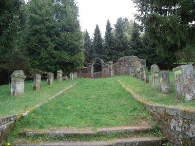 Panoramabild einer Friedhofsallee die auf ein Grabmal zuführt.