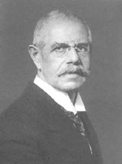 Photographie von Franz Matt im fortgeschrittenen Alter, mit randloser Brille, Anzug und markantem Schnauzbart.