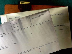 Drei stark mit Ruß geschwärzte Karteikarten auf einem mit "Wei" beschrifteten, ebenfalls verrußten Kartenteiler.